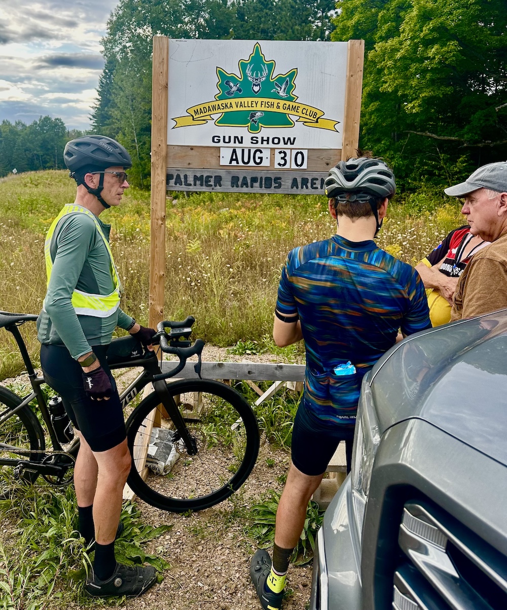 Cyclist at a support stop on the side of the road being provided with snacks.