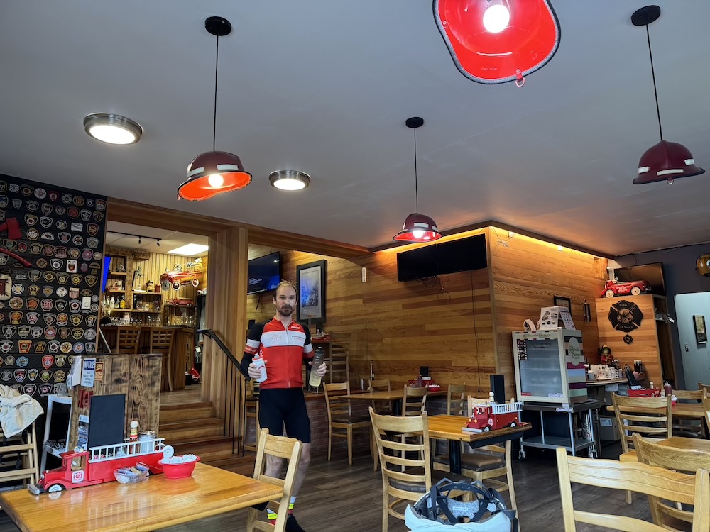 A man in a firefighter-themed diner holding two full water bottles