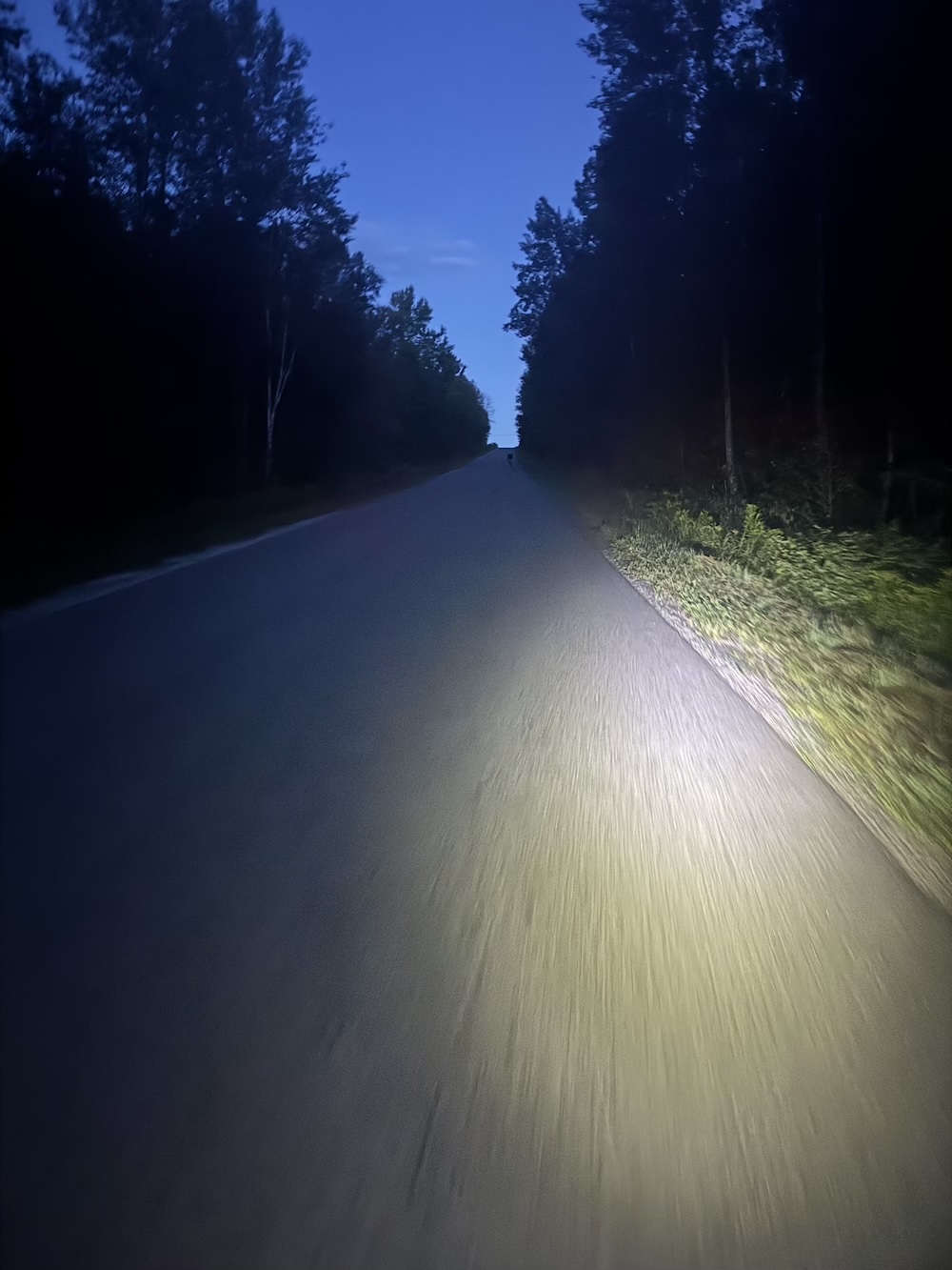 A road lit by a bike light at night going uphill.